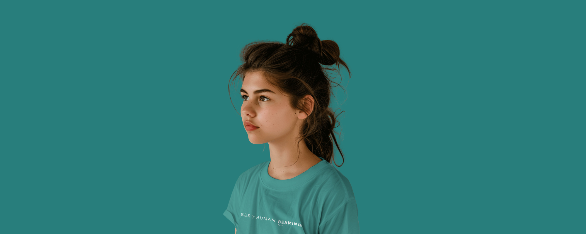Teen girl in a teal Best Human Beaming t-shirt with minimalist white logo, looking to the side against a teal background. Showcases sustainable, empowering, and inclusive youth style.