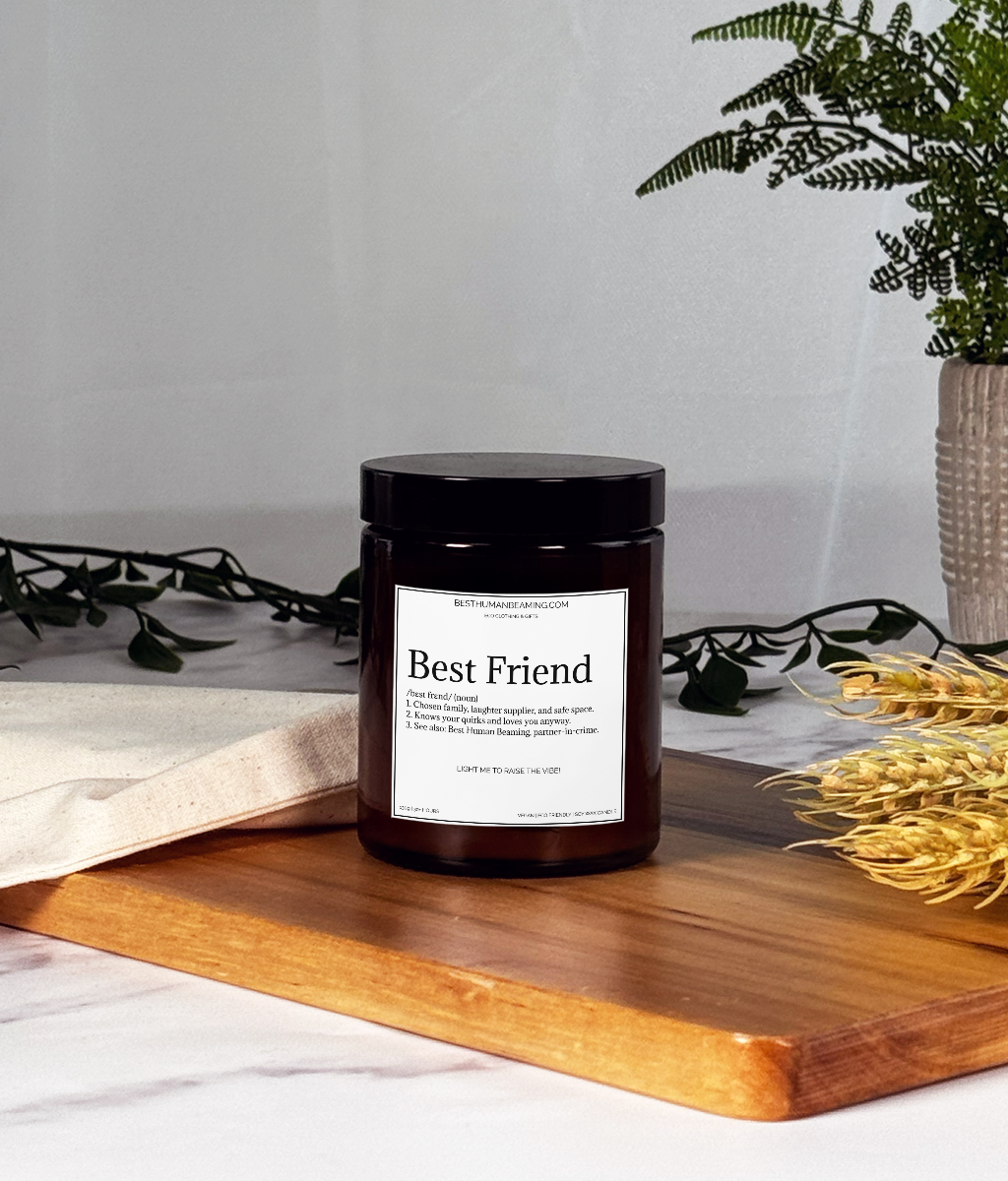 A hand-poured eco-friendly candle in a minimalist glass jar, featuring the Best Human Beaming label. The candle is styled on a clean surface with soft, natural lighting, radiating a warm, inviting glow—perfect for creating a calming and uplifting atmosphere.