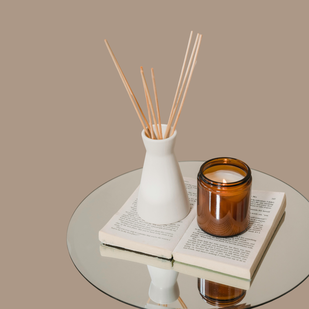 An amber candle on an open book, styled on a mirrored table. Minimalist, calming scene reflecting Best Human Beaming’s focus on mindful, eco-friendly living.