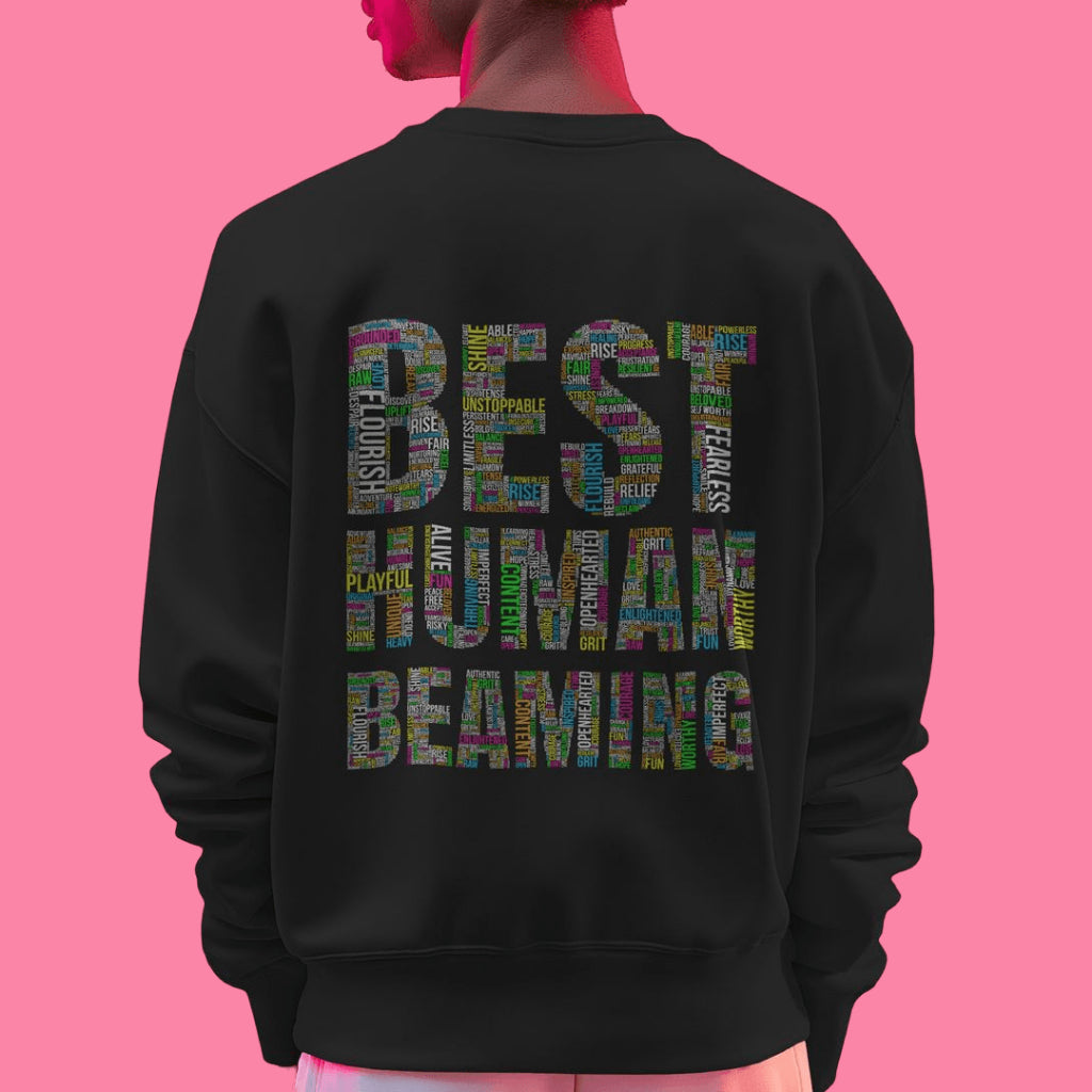 Person from behind in a black Best Human Beaming sweatshirt. “BEST HUMAN BEAMING” is filled with uplifting words in bright colors, promoting confidence and positivity.