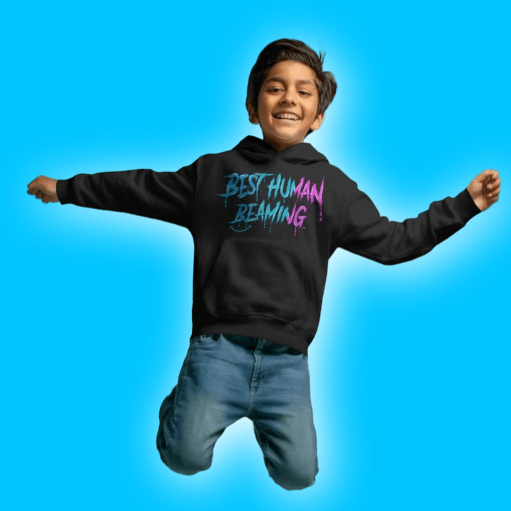 Happy boy jumping in a black Best Human Beaming hoodie with bold blue and pink graffiti-style logo. The image is energetic and fun on a bright blue background.